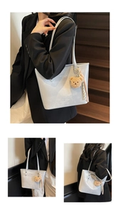 Detail of grey minimalist tote bag with thin straps and a cute brown plush bear charm