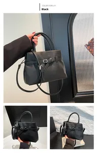 Detail view of black lychee grain leather handbag with belt strap and round handles