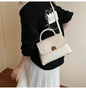 Detailed side view of white lychee leather handbag with golden buckle on a model