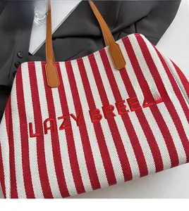 Détail du cabas en toile rayé rouge avec broderie LAZY BREEZE et anses en cuir marron