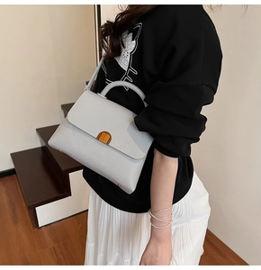 Detail of grey lychee leather handbag with gold metal lock and round handle for women