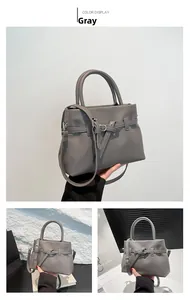 Detail of grey lychee-textured leather handbag with adjustable strap and top handle
