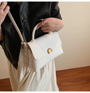 Detail of white lychee leather texture on a square bag with gold metal buckle