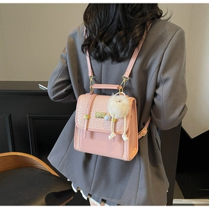 Dettaglio dello zaino in pelle PU rosa con texture trapuntata e pompon bianco morbido