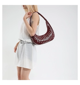 Detail der burgunderroten Lackledertasche mit Nieten und sichelförmigem Punk-Design