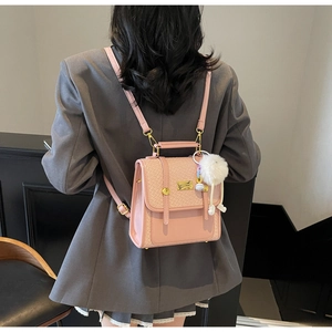 Vista posteriore della modella con zaino rosa, patta intrecciata e pompon bianco