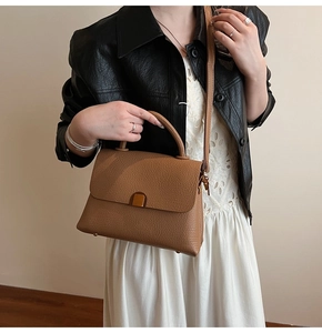 Close-up of brown litchi pattern leather handbag with golden square metal buckle