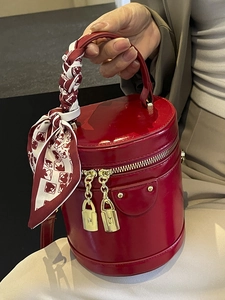 Chic red cylindrical bucket bag in glossy patent leather with silk scarf handle detail