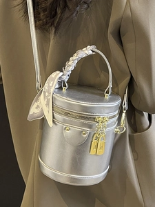 Silver metallic cylinder crossbody bag with scarf-wrapped handle and lock charm