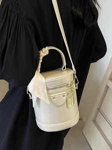 Minimalist cream white cylinder bucket bag with a silk scarf handle and golden lock