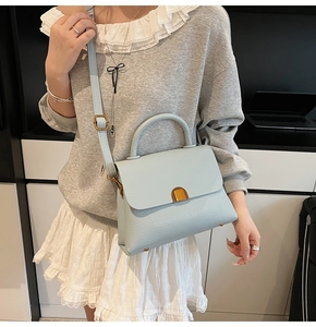 Détail du sac à main bleu clair en cuir grainé avec fermoir métallique doré élégant