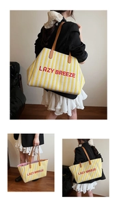 Détail du sac cabas en toile rayée jaune avec broderie LAZY BREEZE et anses en cuir