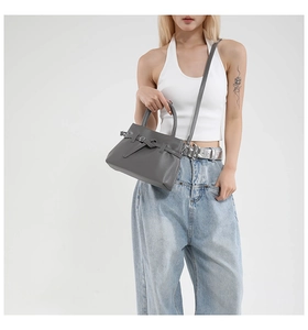 Detailed view of the grey leather handbag with decorative strap and fine texture details
