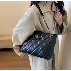 Detail shot of black quilted faux leather handbag with silver chain strap and metal clasp