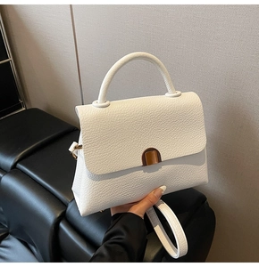 Detail of white lychee grain leather handbag with curved handle and metal arch buckle