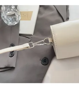 Detailed macro view of cream faux leather handbag with silver metallic hardware and lobster clasp