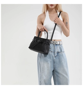 Detail of black litchi grain leather handbag showing buckle strap and fine stitching