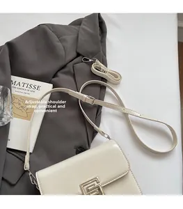 Detailed view of white flap bag with golden metal buckle and adjustable straps on suit