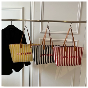 Trois grands sacs cabas en toile rayée jaune, noir et rouge avec le logo Lazy Breeze