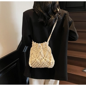 Detail of macrame woven crossbody bucket bag with diamond hollow textures on a model