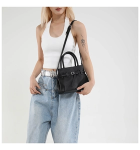 Detail of black lychee grain leather handbag with belt buckle and reinforced handle