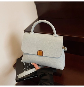 Detailed macro view of light blue lychee pattern leather bag with gold metal buckle