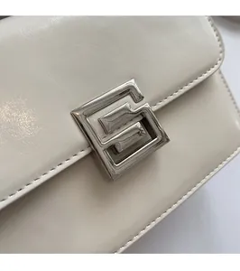Detailed macro shot of the silver geometric lock and textured off-white leather flap bag