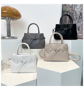 Close-up of four colored lychee pattern leather handbags displayed on a geometric stand