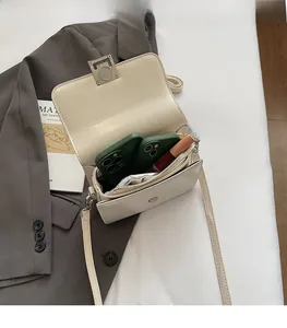 Detail view of cream crossbody bag interior showing multi-layer compartments and silver buckle