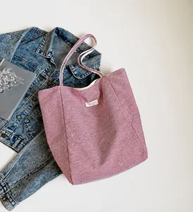 Vista de detalle de un bolso tote de lona a rayas rojas y blancas con etiqueta bordada