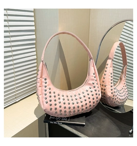 Detailaufnahme der pinkfarbenen Halbmond-Tasche mit silbernen Nieten und weichem Licht
