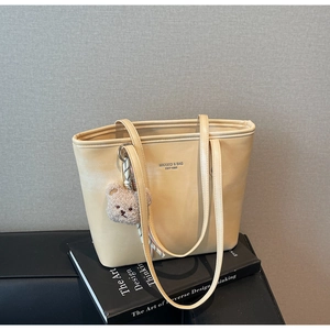 Detail of cream tote bag with teddy charm and silk scarf on a design book