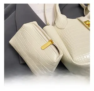 Nahaufnahme der cremeweißen Handtasche mit Krokostruktur und goldenen Metallelementen