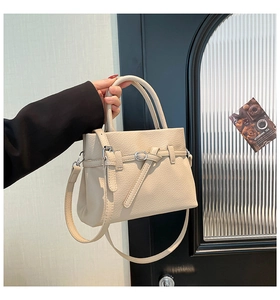 Detailed view of beige pebble grain leather crossbody bag with silver buckle and top handle