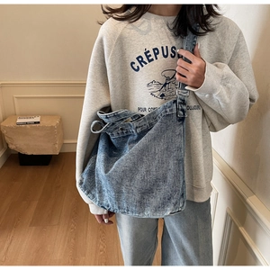 Dettaglio della grande borsa tote in denim lavato blu con tracolla larga e stile retrò