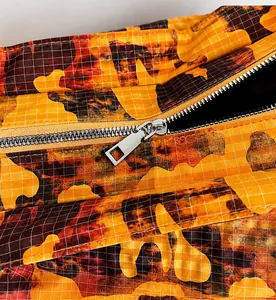 Close-up of smooth silver metal zipper on camouflaged water-dyed fabric backpack
