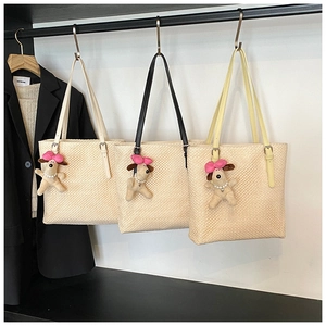 Detailed texture of woven straw tote bags with colorful leather straps and puppy charms