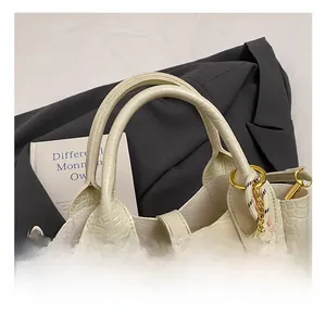 Detail der cremeweißen Beuteltasche mit Steinmuster und Plüschbär-Anhänger