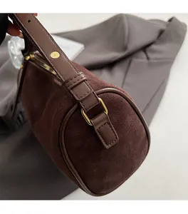Macro view of dark brown suede cylinder bag with premium gold U-shaped hardware details
