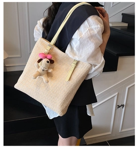 Close-up of woven straw tote bag with leather strap and cute puppy pendant accessory