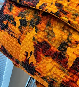 Close-up detail of durable camo fabric texture with orange and brown grid pattern on the backpack