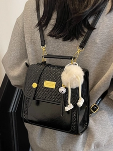 Zaino da donna nero con patta a trama intrecciata e accessorio charm in peluche bianco