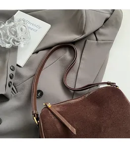 Detail view of dark brown frosted suede cylinder bag with gold hardware and leather strap