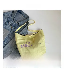 Top view of yellow canvas tote bag with Paris lettering and bow tie detail