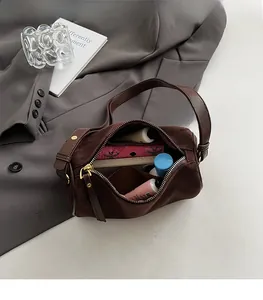 Detailed interior of brown suede cylinder bag showing large capacity and internal pockets