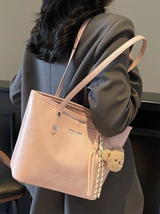 Pink large capacity faux leather tote bag with bear pendant and woven tassels shown on model