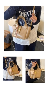 Nahaufnahme der braunen Eimer-Tasche mit Krokostruktur, Goldschließe und Bären-Anhänger