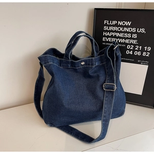 Dettaglio della borsa tote in denim blu scuro con bottone a pressione e tracolla regolabile