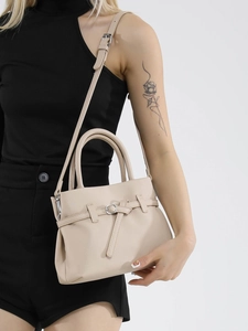 Minimalist beige crossbody handbag with lychee texture held by a model in a black outfit