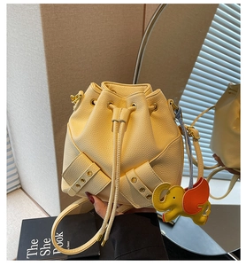 Detail of beige lychee leather bucket bag with gold buckles and cartoon elephant charm